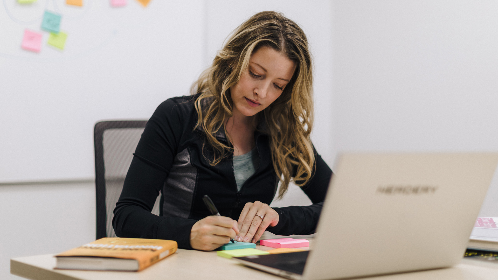 Woman innovating writing stickies strategy laptop