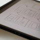 A hand drawing wireframes on a tablet.