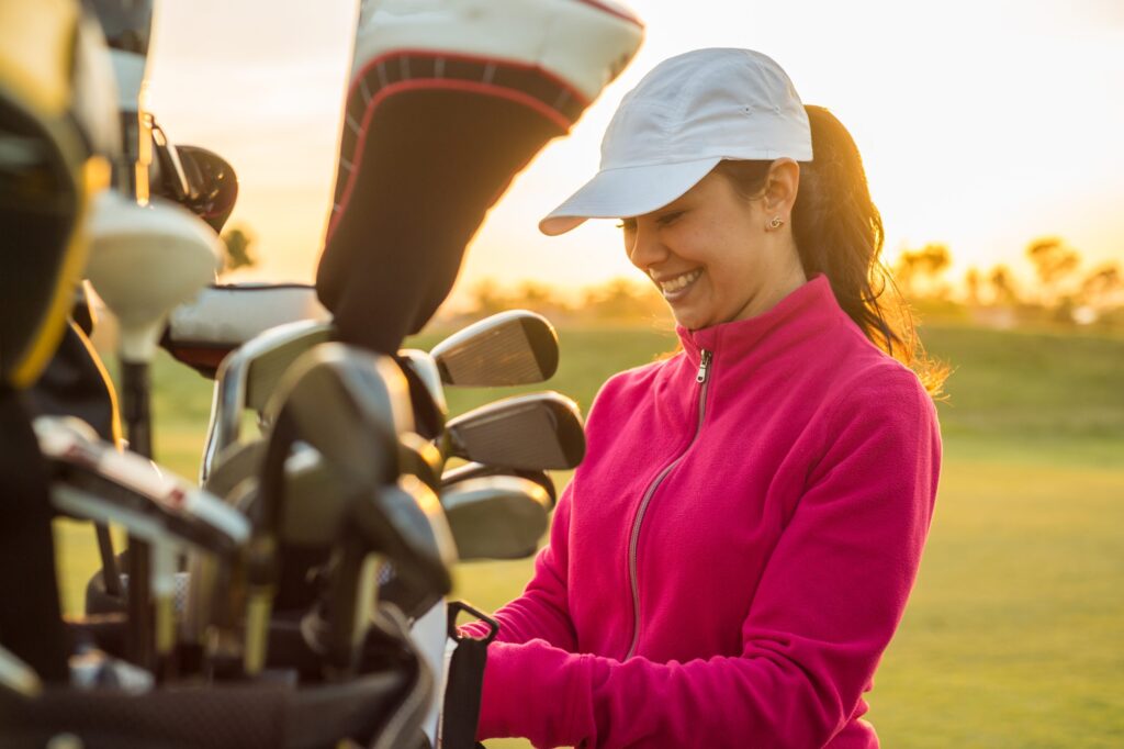 Woman standing next to her golf clubs