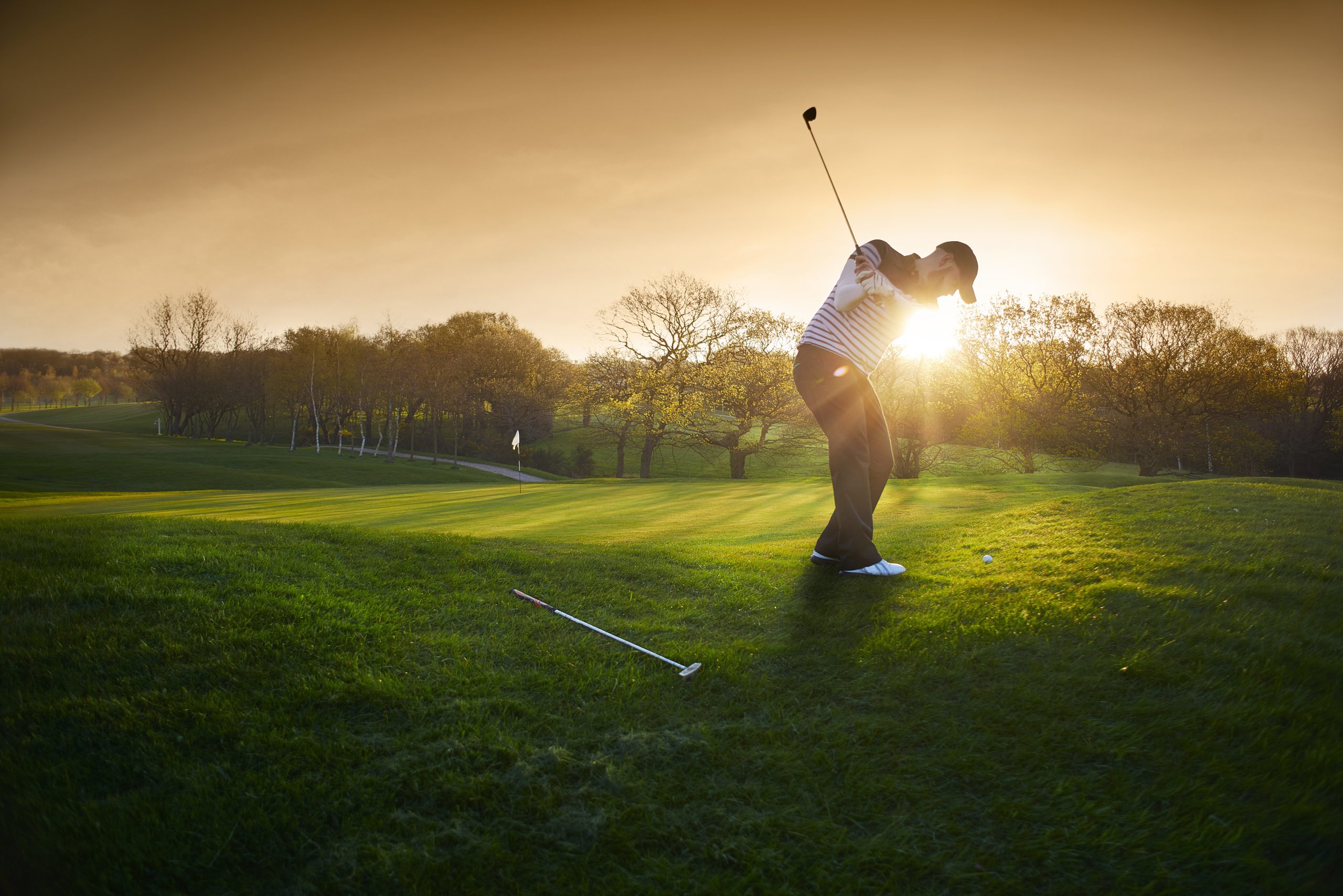 Person playing golf at sunset