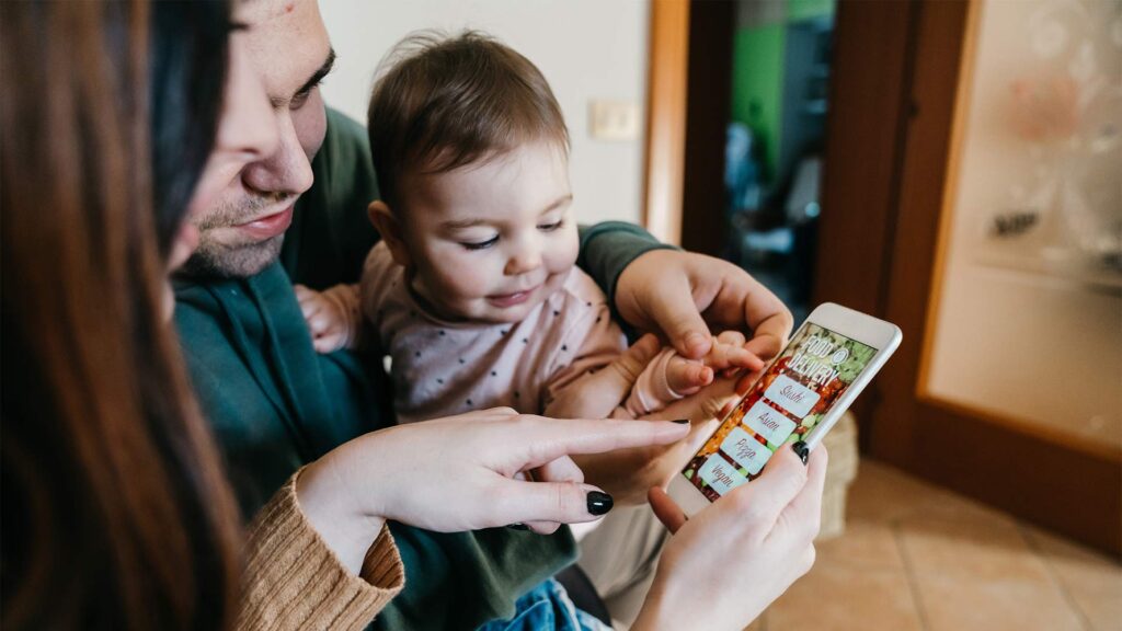 Family with a baby ordering groceries on a mobile phone