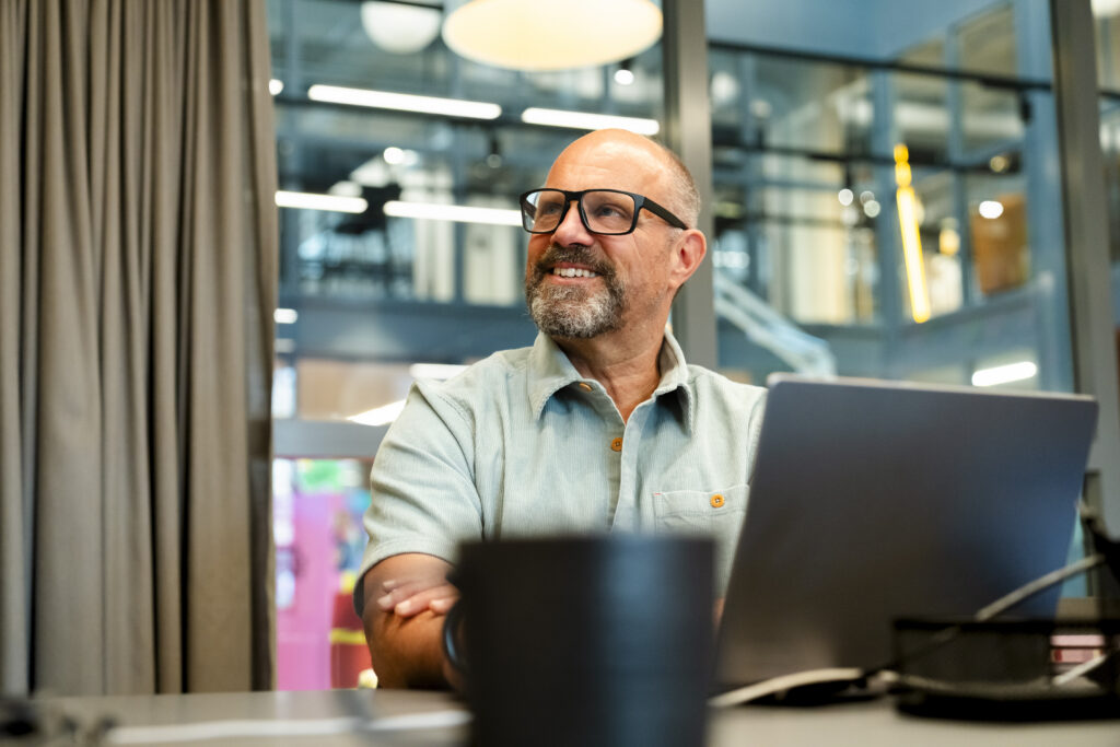 Smiling senior businessman doing online meeting with colleague at office